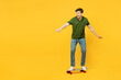 Full body side profile view caucasian active young happy man he wears green t-shirt casual clothes riding skateboard pennyboard isolated on plain yellow background studio portrait. Lifestyle concept.