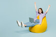 © ViDi Studio - Full body young happy IT woman she wear purple shirt yellow t-shirt casual clothes hold use work on laptop pc computer do winner gesture isolated on plain pastel light blue background studio portrait.