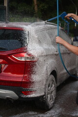 washing a car outside, a red car at a car wash, outdoor