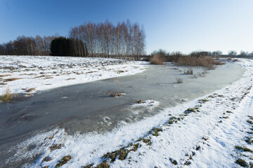 Wall Mural - Frozen snow and water on a rural field