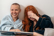 © Konstiantyn Zap - Joyful interaction in a pair of lesbians while reading a book. Joy and pleasure from joint leisure. A woman with short hair and a girl with long red hair.
