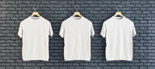 Three Empty White T-shirts Hanging On Black Brick Wall Background. Ad, Textile And Fashion Concept. 3D Rendering.