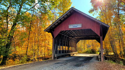 red, wooden, covered brookdale bridge with beautiful autumn colors, stowe, vermont, usa