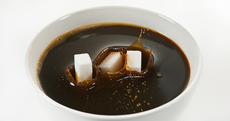 Wall Mural - Sugar Falling into Bowl of Coffee against White Background