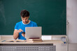 © Elnur - Young male student holding smartphone in the classroom