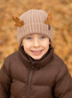 © Marina - Little cute boy with deer horns made of oak leaves sits in yellow foliage
