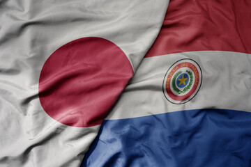 big waving national colorful flag of japan and national flag of paraguay .