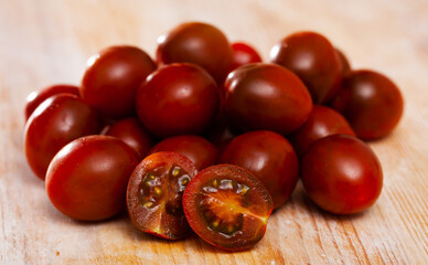 Wall Mural - Closeup of fresh ripe kumato tomatoes on wooden surface. Organic vegetables concept