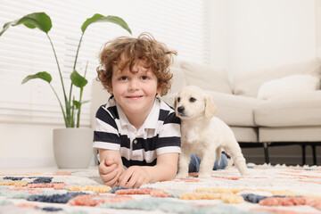 Poster - Little boy with cute puppy on carpet at home