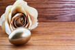 Gold nest egg with beige rose shows successful investing