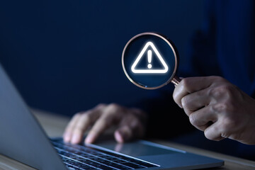 Wall Mural - businessman using laptop showing warning triangle and exclamation sign icon warning of dangerous pro
