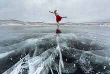 The Lady In A Red Skirt Is Doing Ice Skating On Frozen Lake Baikal. Hills In The Background.