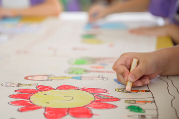 Close-up shot of hands of children drawing and painting water or crayons on paper of their own creative creativity in bright colors in kindergarten class in school.