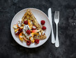 Oatmeal pancake made of whole grain flakes and eggs with fruits, berries and Greek yogurt on a dark background, top view