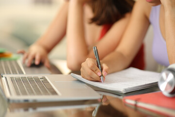 Students hands using laptop and taking notes