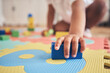 © Azee Jacobs/peopleimages.com - Building blocks, hands and toddler at daycare with development on number carpet and ground. Learning, baby and toy with nursery, motor skills and child game at kindergarten with youth and cube