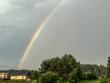 Fototapeta Tęcza - Rainbow, over trees and village buildings, in the sky after the rain