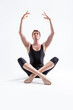 © danmorgan12 - Male Ballerino Dancer Sitting While Practising Legs and Arms Stretching Exercices In Black Sportive Tights in Studio.