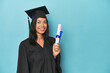 © Asier - Celebrating Filipina graduate with diploma and cap on blue studio