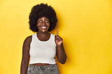 African-American Woman With Afro, Studio Yellow Background Showing Number One With Finger.