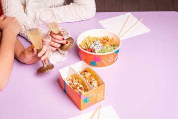 Attractive couple of casual caucasian girls eating delicious poke, japanese fresh healty food, during lunch. Young white pretty women relaxing talking eating tasty sushi sitting at table on a date