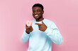 © Богдан Маліцький - african man in blue sweater eats sweet donuts on pink isolated background, man with pastries and food smiles