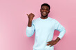 © Богдан Маліцький - african american man in blue sweater smiles and shows his hand to the side on pink isolated background
