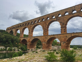 Panoramic view of ancient old Roman Aqueduct Pont du Gard ear Vers-Pon-du-Gard, Occitanie, France, Europe. Landmark over the River Gardon. Unesco world heritage site near Nimes, Languedoc-Roussillon