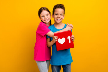 Sticker - Photo of adorable sweet preteen schoolkids dressed t-shirts hugging holding heart like sign isolated yellow color background