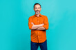 © deagreez - Photo of positive charming guy wear orange shirt arms folded smiling isolated teal color background