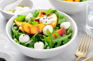 Wall Mural - Grilled Peach Salad with Arugula and Mozzarella on Bright Concrete Background