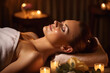 © uv_group - Portrait of young woman at spa in dark light with candles and lights , massage and relax concept