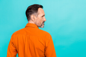 Wall Mural - Portrait of handsome cool man dressed orange shirt with stylish beard standing with his back turned isolated on turquoise color background
