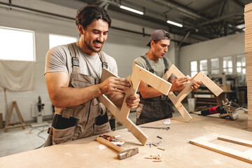 Wall Mural - Two young men carpenters making furniture in warehouse of wood factory