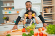 © chokniti - black people family in cook time, people who father and mother with child or girl daughter having smile and happy to cooking a food in kitchen at home, fun making vegetables salad for healthy together