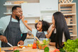 © chokniti - Kind African american parents teaching their adorable daughter how to cook healthy food, free space of kitchen, Happy black people family preparing healthy food in kitchen together