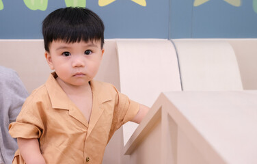 Portrait of adorable toddler asian little boy looking camera standing in children room.