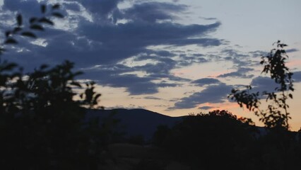 Wall Mural - Sunset with clouds in mountains timelapse 4K video.