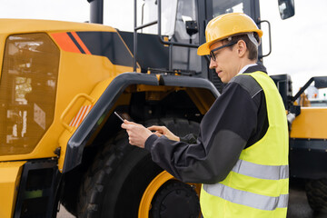 Aufkleber - Worker in a helmet with a digital tablet on the background of construction machine.