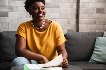 Brazilian woman smiles and looks to the side on sofa in living room at home