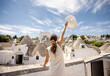 A young woman in a white dress and a hat during tourist visit in Alberobello, Italy