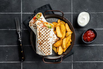 Wall Mural - Shawarma Shaurma kebab with meat, vegetable salad and french fries. Black background. Top view