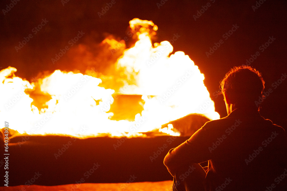 Silhouette of man sitting by a roaring fire. Stock Photo | Adobe Stock