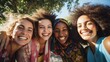 © EVGENIA - Cheerful African, African American and Caucasian young women laugh looking at camera closeup. Multiracial females pose standing in summer park under blue sky. Racial diversity and equality of people
