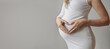 Pregnant woman making heart shape on stomach, Young pregnant woman doing heart gesture on belly