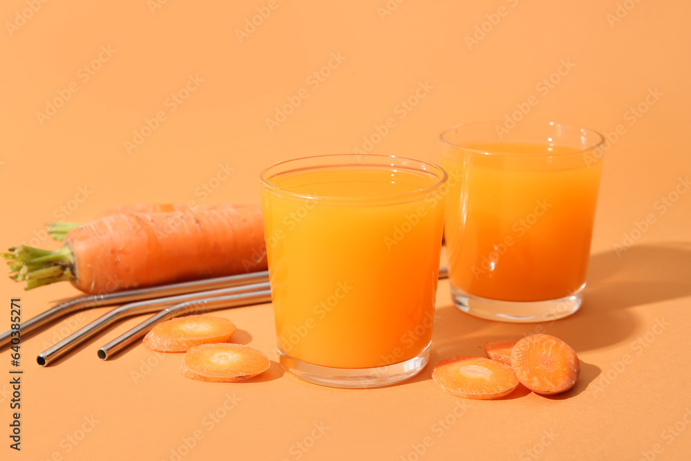 Glasses of fresh carrot juice on orange background