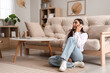 © Pixel-Shot - Young woman talking by mobile phone in living room