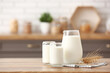© Pixel-Shot - Glasses and jug of fresh milk with wheat ears on wooden table in kitchen