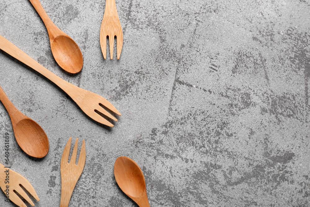 Wooden spoons and forks on grey background