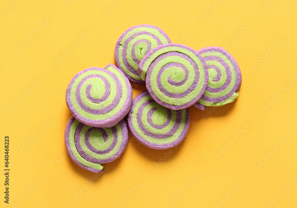 Tasty cookies for Halloween celebration on yellow background